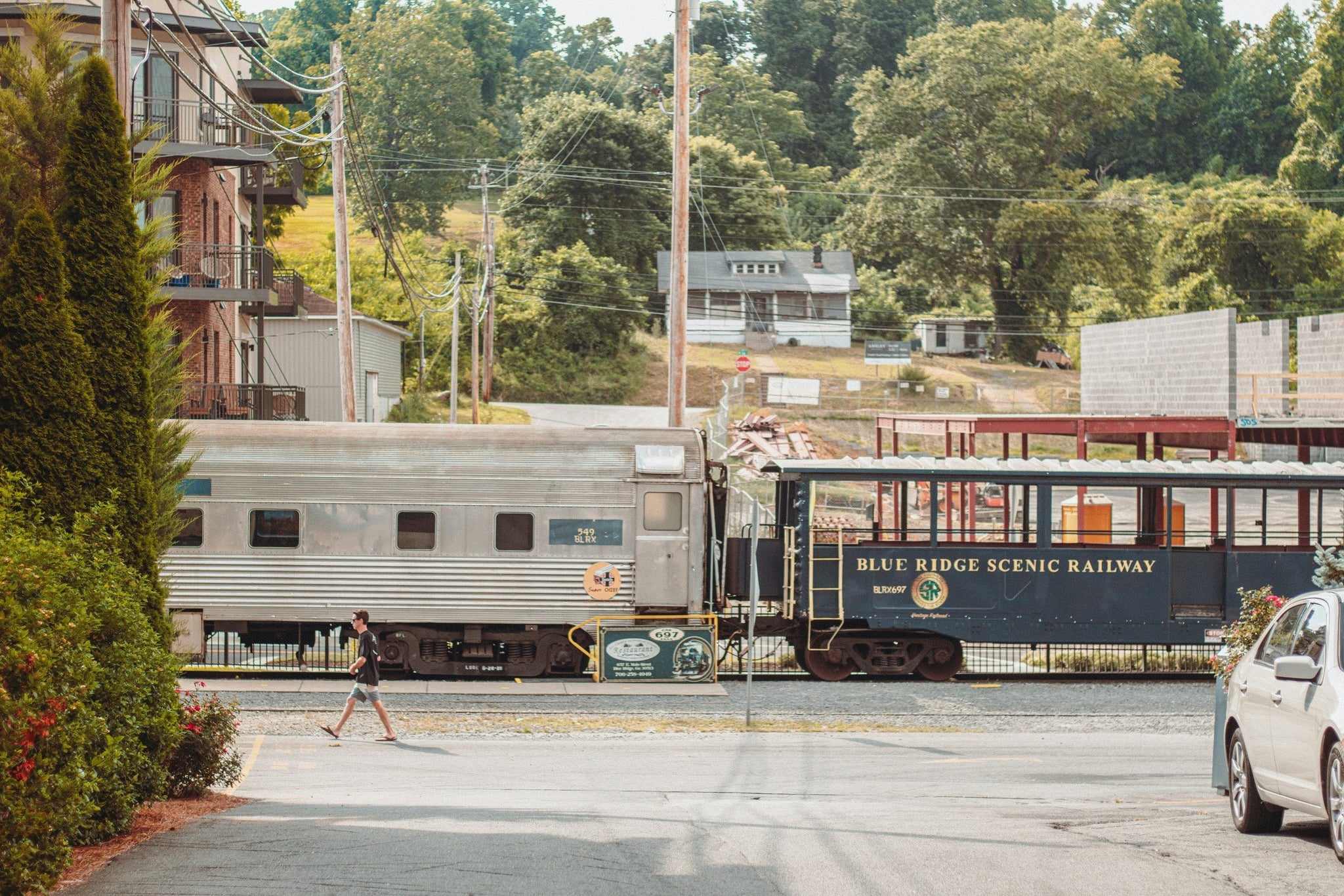 Blue Ridge Scenic Railway passenger car on tracks with a pedestrian nearby and green trees in the background